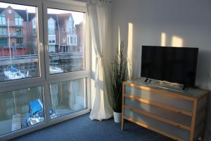 einen Fernseher auf einer Kommode vor einem Fenster in der Unterkunft Ferienhaus Hafenzeit in Cuxhaven
