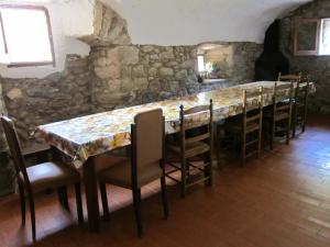een lange tafel met stoelen en een stenen muur bij Mas el Llach in La Vall de Bianya