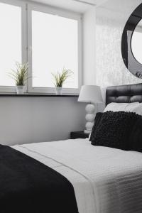 a bedroom with a black and white bed and two windows at Grodzka Apartament Centrum in Słupsk