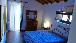 ein Schlafzimmer mit einem blauen Bett, einer Kommode und einem Fenster in der Unterkunft Piccolo Casale in Milazzo