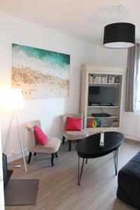 a living room with a couch and chairs and a tv at Appartement Quai Ouest in Dieppe