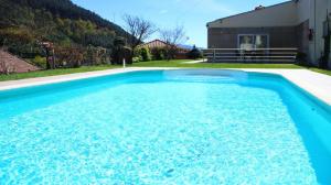 a large blue swimming pool in front of a house at Casinhas do Gerês in Geres +40 photos