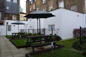 a picnic table with an umbrella in a courtyard at Studios2Let - North Gower in London