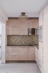 a kitchen with white cabinets and a chandelier at Apartament Hubalczyków in Słupsk
