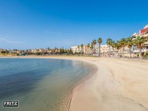 una spiaggia con palme, edifici e acqua di Landmark Apartment a Birżebbuġa