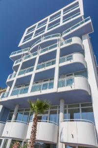 a tall building with a palm tree in front of it at Hotel Mediterraneo in Sottomarina