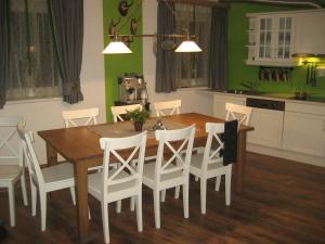 - une cuisine avec une table en bois et des chaises blanches dans l'établissement Alpen Chalet Eben, à Eben im Pongau