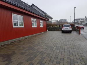a car parked in a parking lot next to a red building at Comfy in the center in Tórshavn