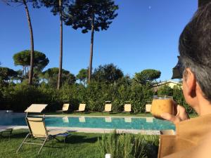 a man holding a drink next to a swimming pool at Arli Hotel Hideaway Punta Ala - Adults Only in Punta Ala