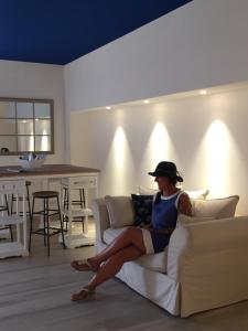 a woman sitting on a couch in a living room at Arli Hotel Hideaway Punta Ala - Adults Only in Punta Ala