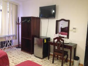 a living room with a desk and a mirror and a television at Hotel Claudia in Macuspana