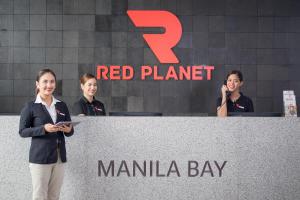 three women standing behind a red planet marina bay sign at Red Planet Manila Bay in Manila