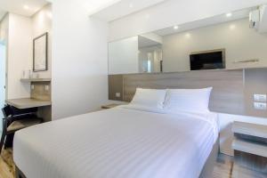 a bedroom with a large white bed and a mirror at Red Planet Manila Bay in Manila