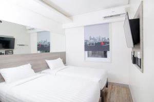 a white bedroom with a bed and a tv at Red Planet Manila Bay in Manila