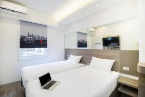 two beds in a hotel room with a laptop on the bed at Red Planet Manila Bay in Manila