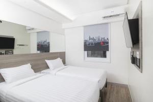 two beds in a white room with a window at Red Planet Manila Bay in Manila