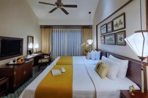 a hotel room with a large bed and a flat screen tv at Little Hoi An . A Boutique Hotel & Spa in Hoi An