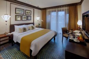 um quarto de hotel com uma cama grande e uma secretária em Little Hoi An . A Boutique Hotel & Spa em Hoi An
