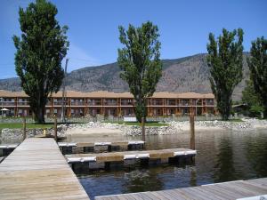 a building with a dock in the water with trees at Casa Del Mila Oro in Osoyoos