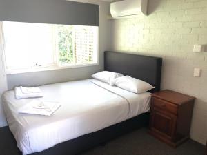 a bedroom with a large white bed with a window at Bateau Bay Hotel in Bateau Bay