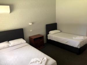 a hotel room with two beds and a night stand at Bateau Bay Hotel in Bateau Bay