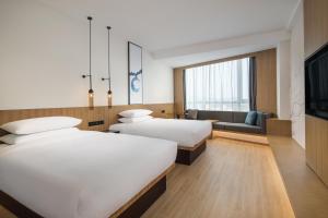 a hotel room with two beds and a couch at Fairfield by Marriott Dongguan Changping in Dongguan