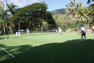 people playing tennis on a tennis court at Amaroo On Mandalay in Nelly Bay