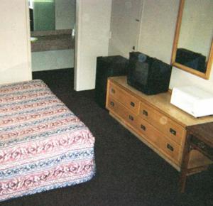 a bedroom with a bed and a dresser with a tv on it at Royal Extended Stay in Alcoa