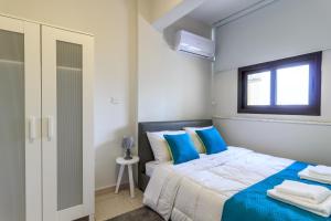 a bedroom with a bed with blue pillows and a window at SOHO City Apartments in Larnaca