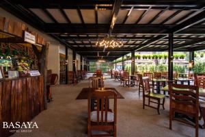 a restaurant with wooden tables and chairs and a chandelier at Basaya Beach Hotel & Resort in Pattaya Central