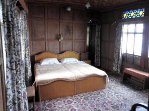 a bedroom with a bed in a room with a window at Butts Clermount Houseboat in Srinagar