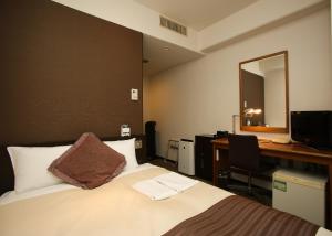 a hotel room with a bed and a desk and a mirror at Koriyama Washington Hotel in Koriyama