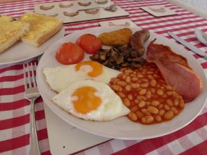 a plate of breakfast food with eggs beans and bacon at Manor Farm Stay in Sutton on Sea