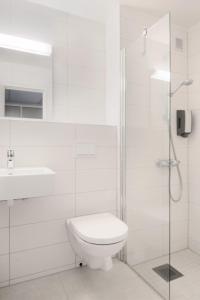 a white bathroom with a toilet and a shower at Oscarsborg Castle Hotel & Resort in Drøbak