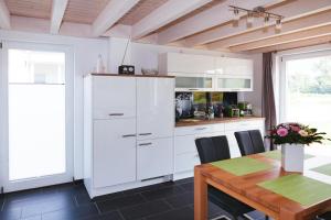 ノルトホルンにあるFerienhaus "Mooie Tied"の白いキャビネットと木製テーブル付きのキッチン