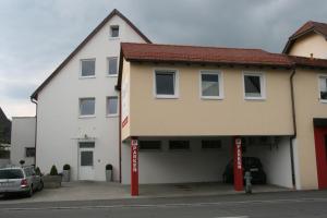 a white building with red poles in front of it at Wendlers Ferienwohnungen #2 und #3 in Schwaig bei Nürnberg