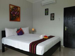 a bedroom with a white bed with a stuffed animal on it at CF Komodo Hotel in Labuan Bajo