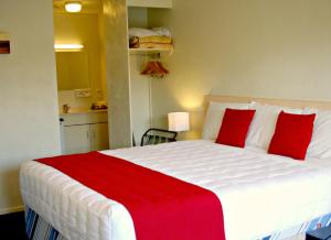 a bedroom with a large white bed with red pillows at Abbots Hamilton – Hotel and Conference Centre in Hamilton