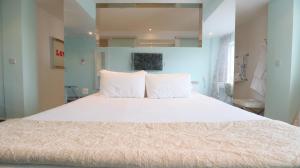 a bedroom with a large bed with white pillows at Citrus Hotel Cheltenham by Compass Hospitality in Cheltenham