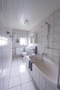 uma casa de banho com uma banheira, um WC e um lavatório. em SOVA Pension Fuldatal em Fuldatal
