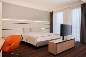 a hotel room with a bed and a television at Hyperion Hotel Hamburg in Hamburg
