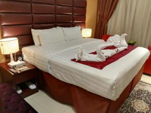 een hotelkamer met een groot bed met 2 personen in handdoeken bij فندق الأصيل ألوان الفندقية in Mekka