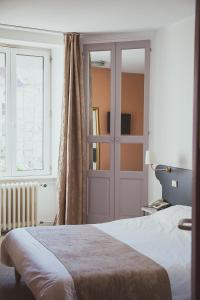 a bedroom with a bed and a door and a window at Hôtel Logis Le Bourbon in Yssingeaux