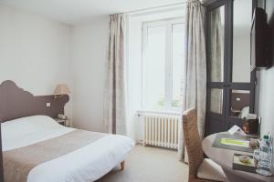een slaapkamer met een bed, een bureau en een raam bij Hôtel Logis Le Bourbon in Yssingeaux