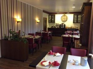 a restaurant with tables and chairs and a clock on the wall at Hotel Pension Berghaus Sieben in Bad Laasphe
