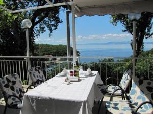 una mesa y sillas blancas con vistas al océano en Boarding House Lucija en Kostrena