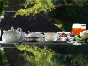 a tea set on a table with cups and drinks at Le Clos des Pommiers in Blainville-sur-Mer
