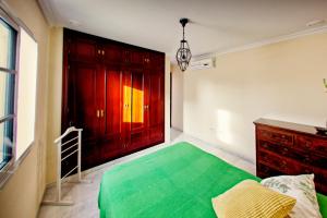 1 dormitorio con 1 cama verde y armarios rojos en El Ático de Cervantes, en Cádiz