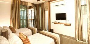 a hotel room with two beds and a television at Infinity Resort in Puerto Galera