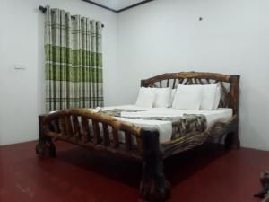 ein Holzbett mit weißen Kissen in einem Zimmer in der Unterkunft Aralu Habarana Resort in Habarana